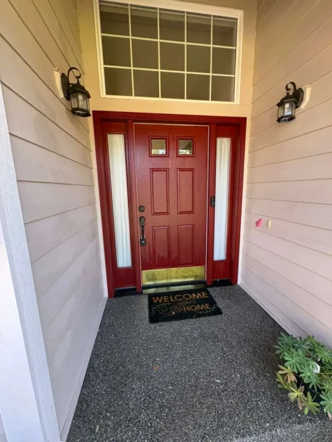 Front entry with neutral siding and red door before exterior repainting