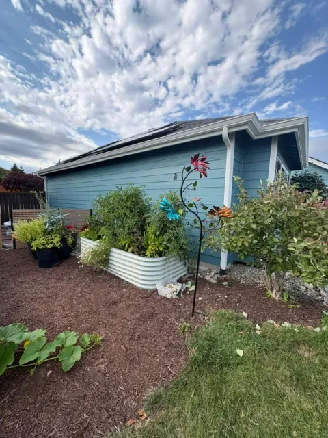 Finished blue side elevation with white trim beside a landscaped garden