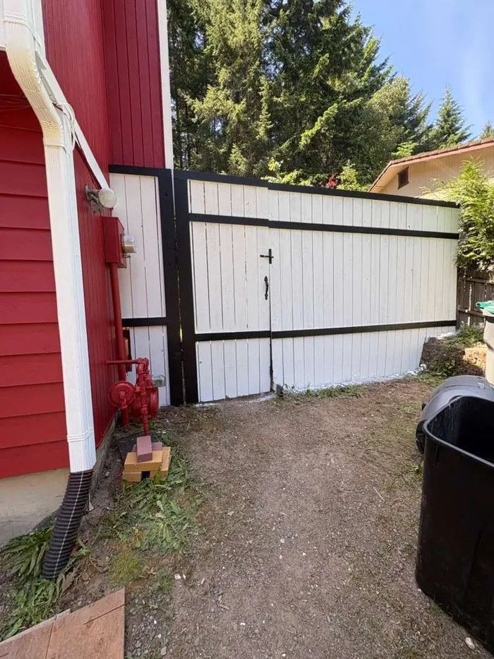 Exterior paint detail showing fence and trim transitions beside red siding