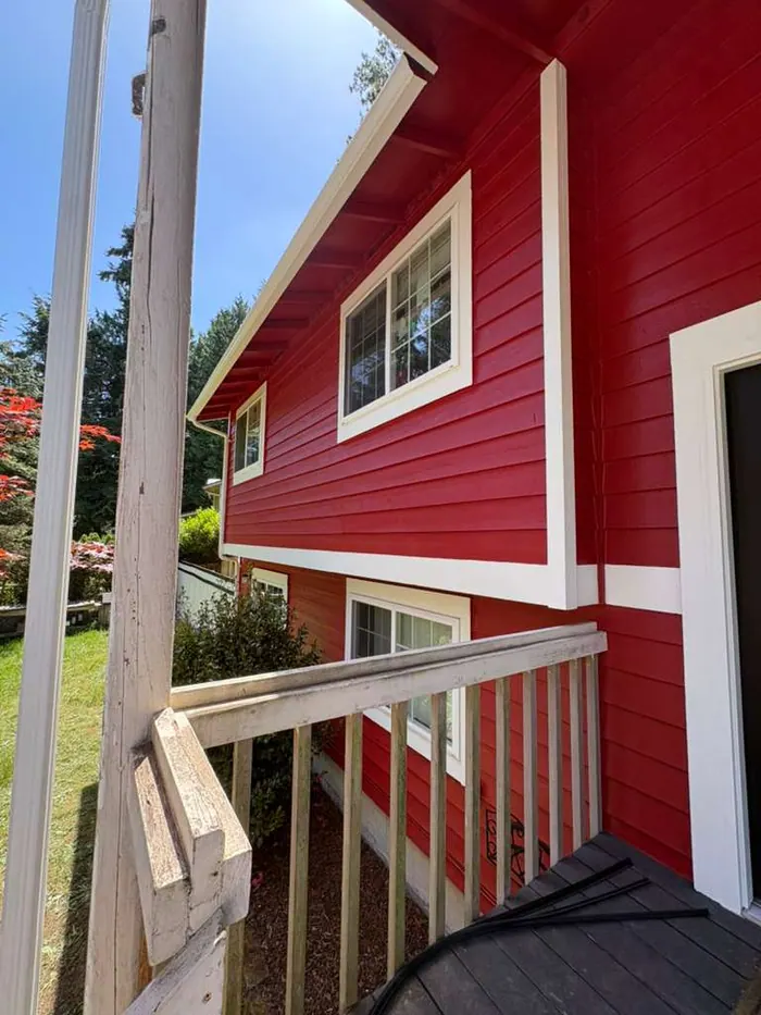 Finished porch railing and window trim beside red exterior siding