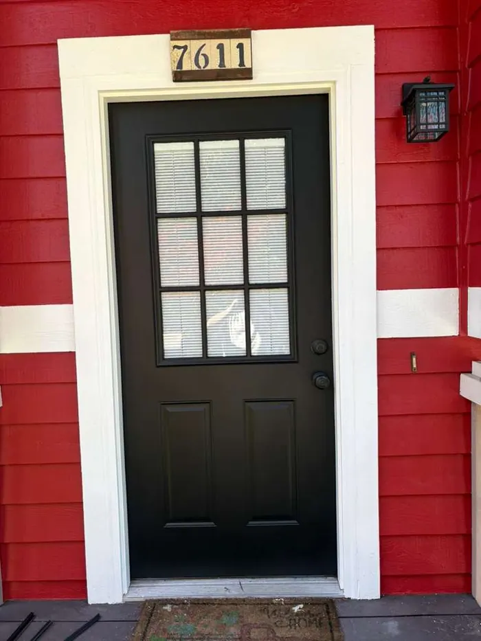 Finished black front door with white trim and red exterior siding